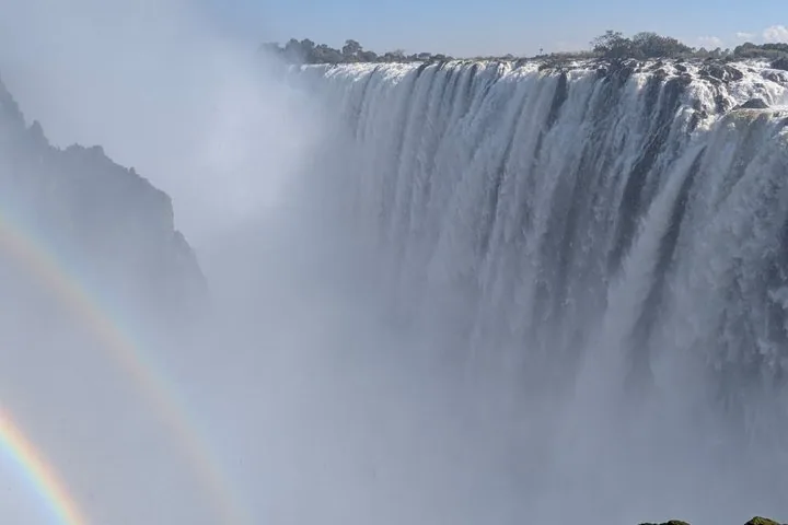 Les chutes Victoria avec de la brume et un faible arc-en-ciel visible sur la gauche.